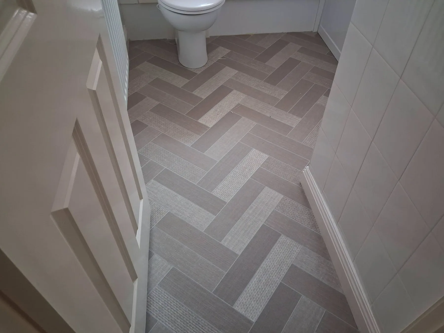 Muted herringbone patterned flooring fitted in a bathroom